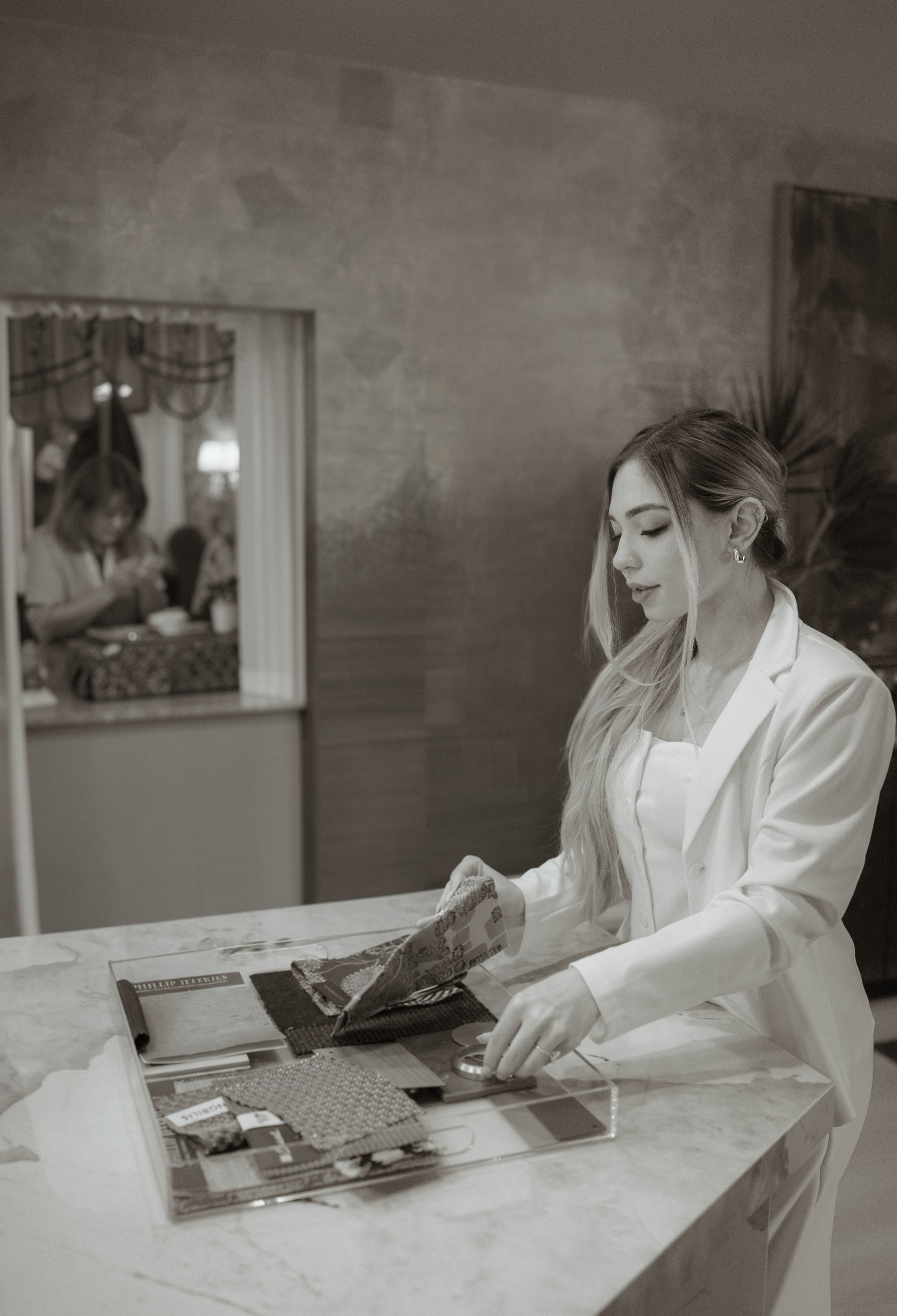 Isabella Longobardi reviewing fabric, wallcovering and trim samples on a marble counter in the studio.