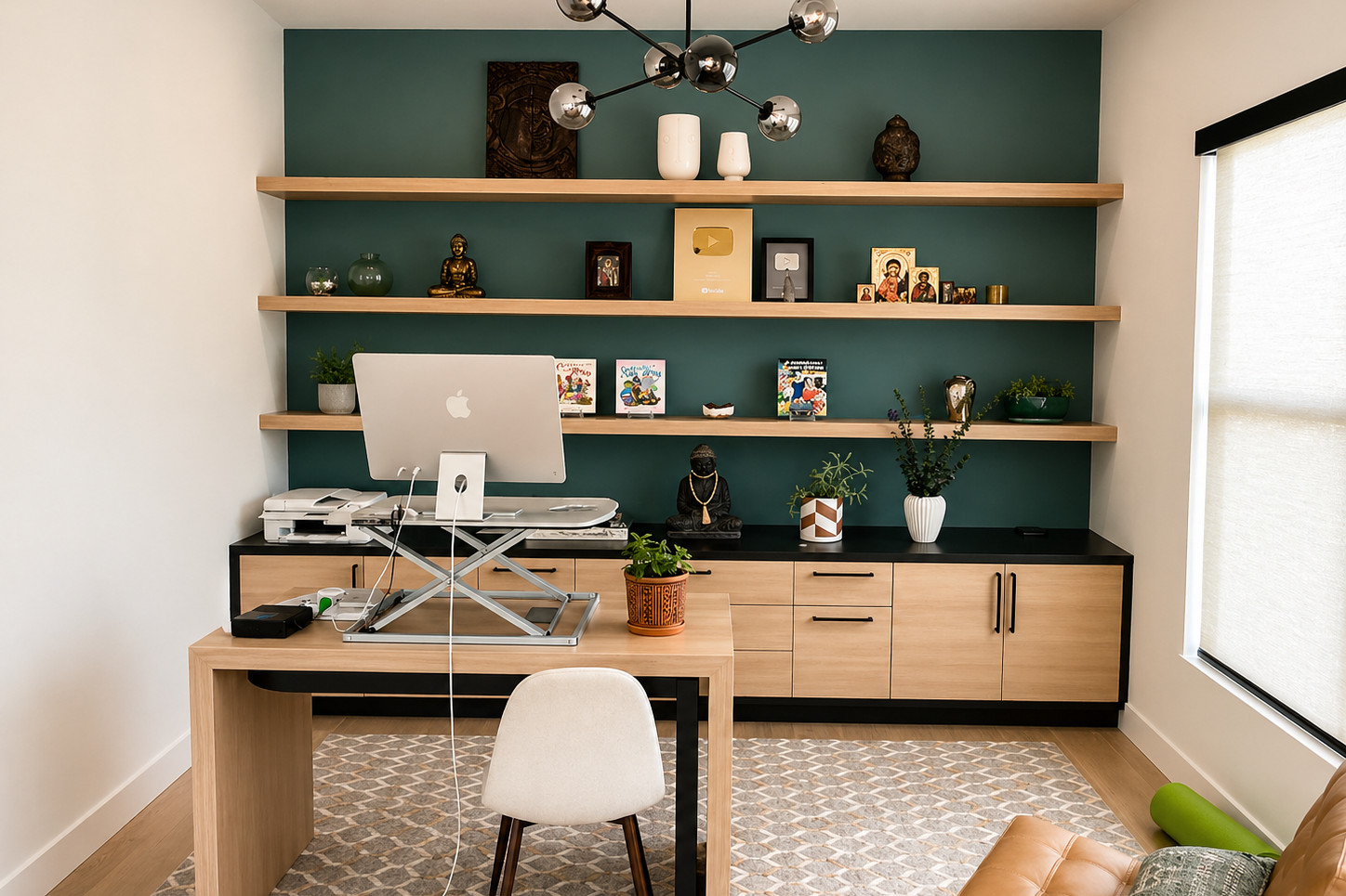 Styled home office with a teal accent wall, floating white oak shelves holding art objects and books, a black-topped oak credenza, and an oak desk with a sit-stand riser.