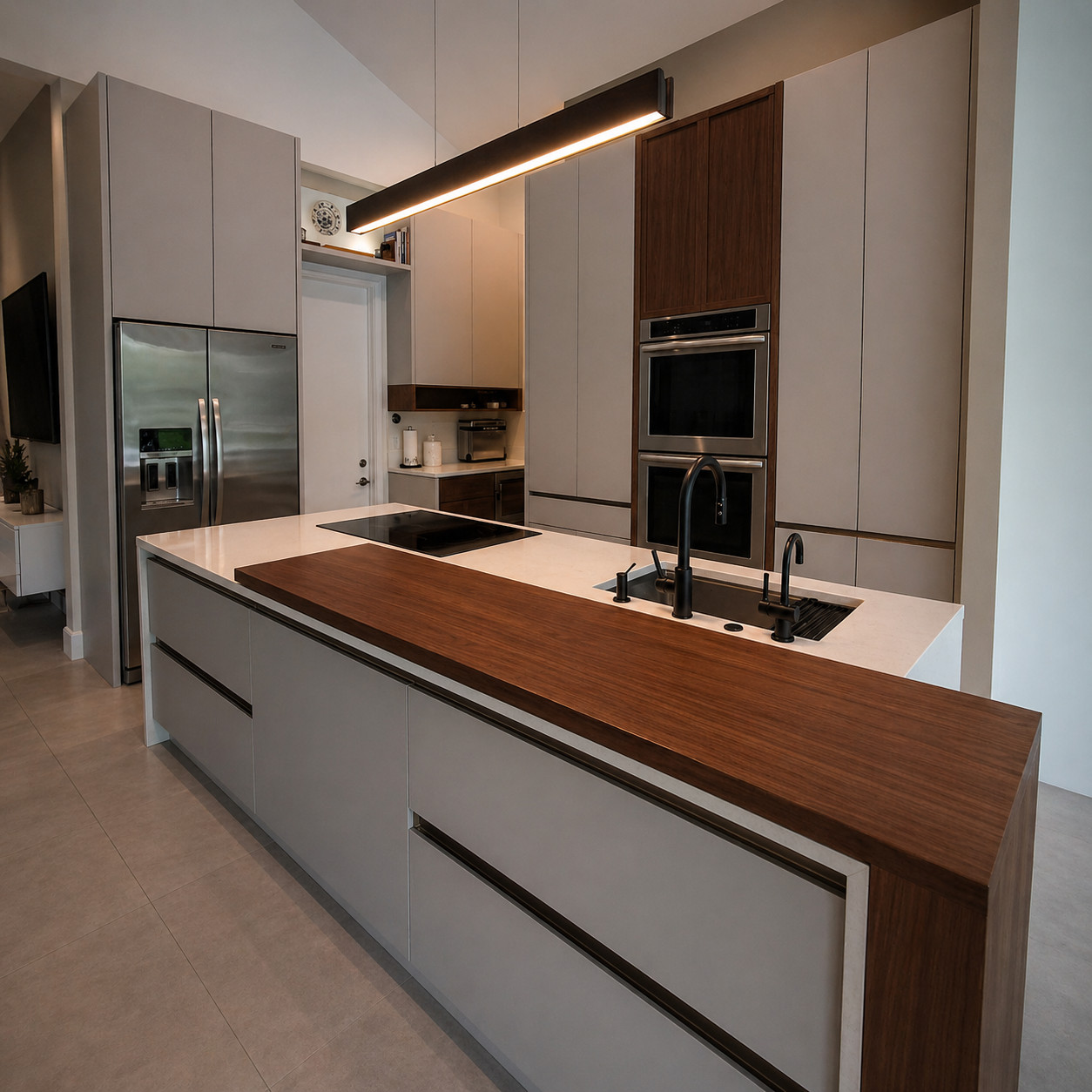 Contemporary kitchen island with a walnut waterfall bar top over a white quartz counter, handleless greige slab cabinets, matte black faucets, a stainless double wall oven and a linear black pendant light.