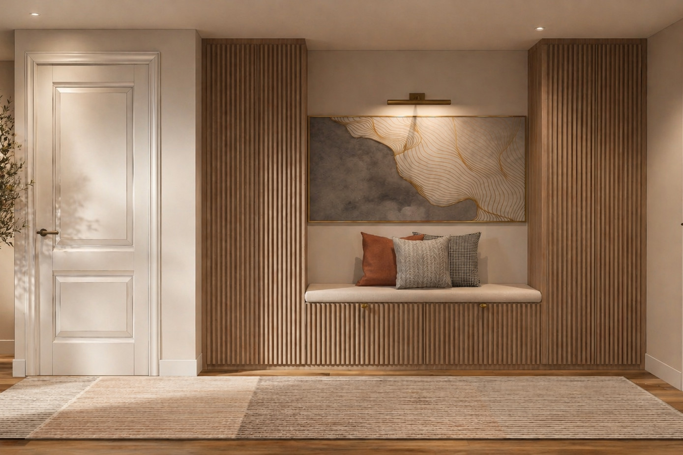 Entry hall with a floor-to-ceiling wood slat wall, a built-in upholstered bench with a fluted base and throw pillows, framed abstract art under a brass picture light, an olive tree in a stone planter and a neutral rug.